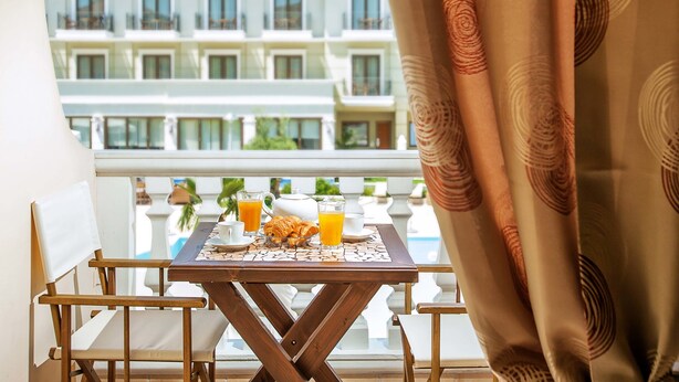 A balcony with a table set for breakfast, including croissants, juice, and coffee. - Casa Di Mare Poseidon (Katerini)