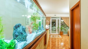 A hallway with a large aquarium, a wooden door, and a tiled floor. - Casa Di Mare Poseidon (Katerini)