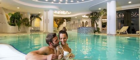 Een binnenzwembad, een buitenzwembad en parasols bij het zwembad