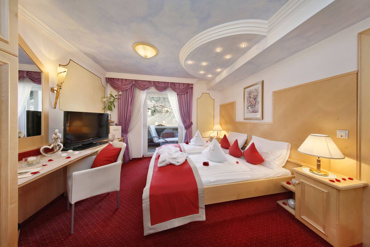 A hotel room with a bed, a desk, a television, and a window with curtains.