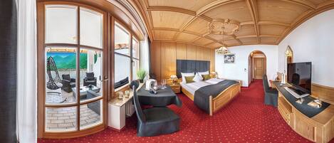 A hotel room with a large window, a bed, a desk, and a TV.