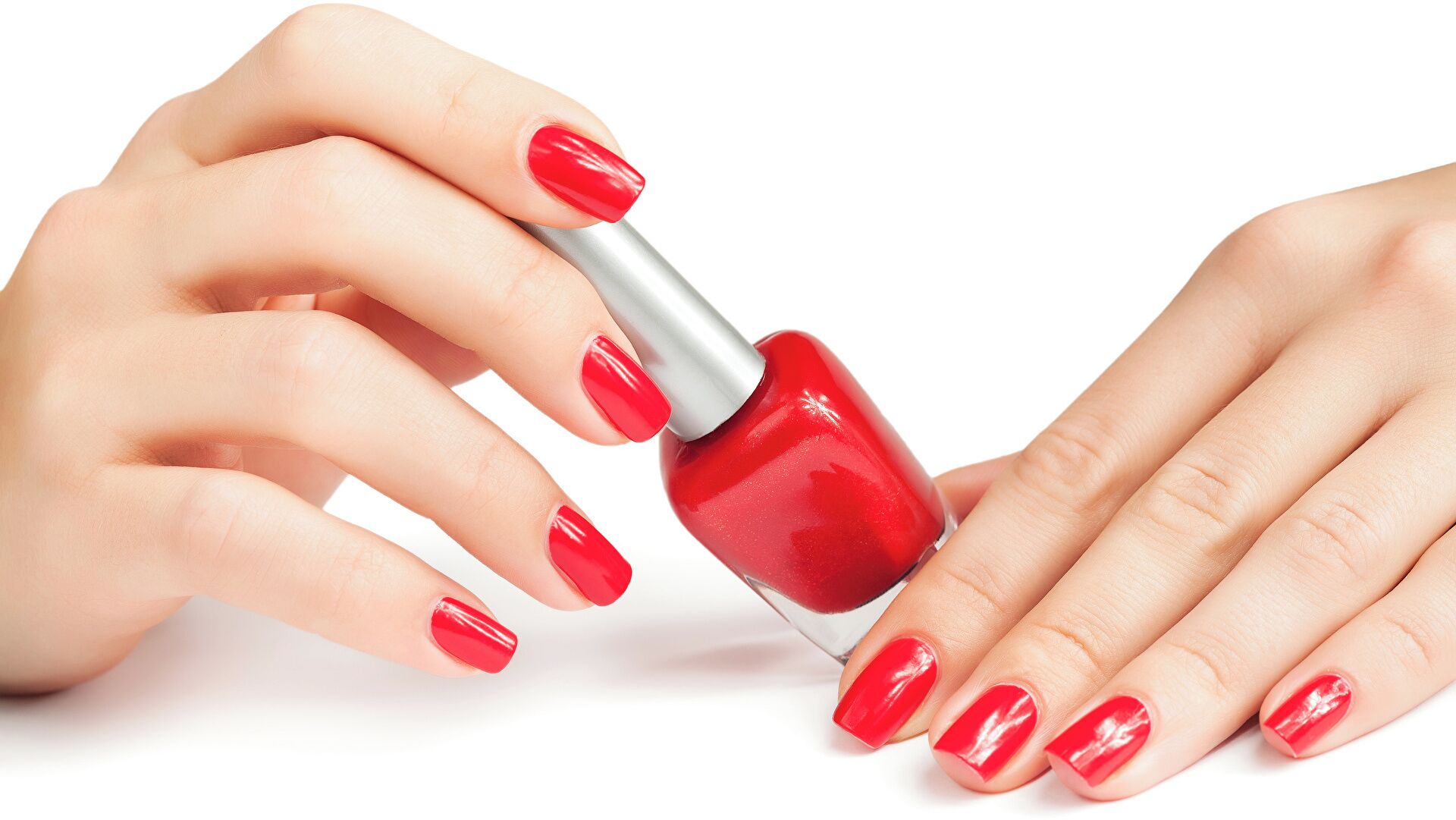Twee handen die nagels rood kleuren.