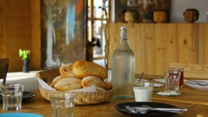 Une table en bois avec un panier de pain, une bouteille et des verres.