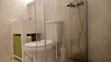 A bathroom with a toilet, a shower, and a sink.