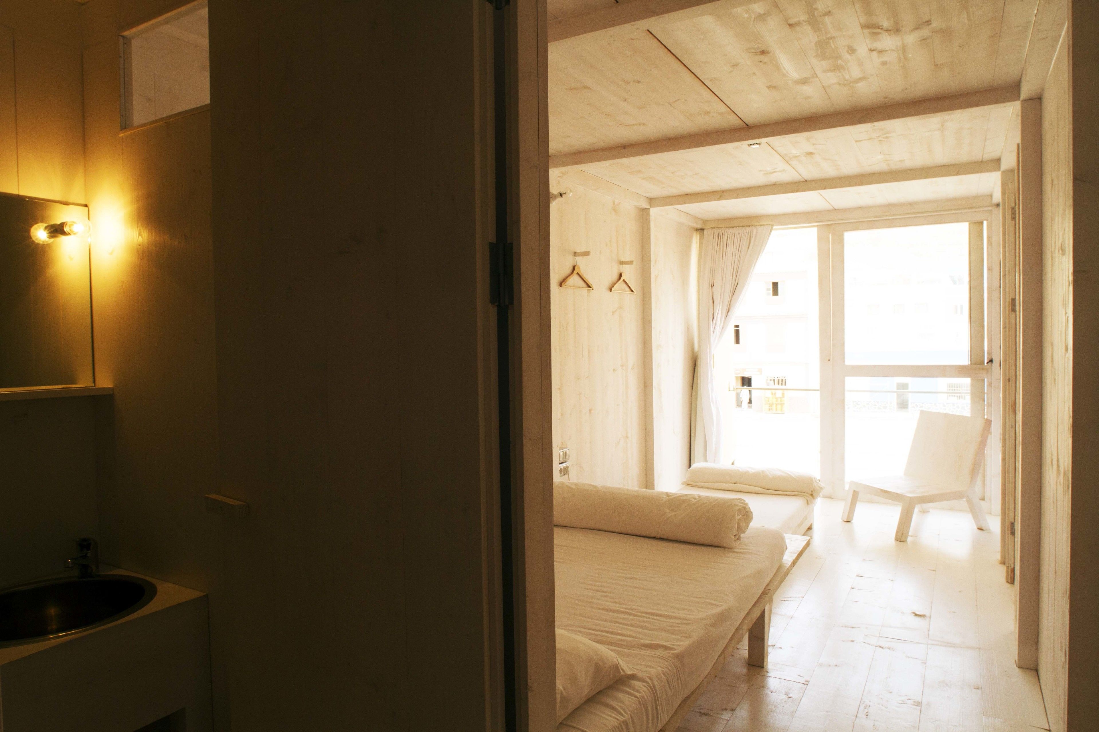 A room with a bed, a chair, a hanging light fixture, and a window with curtains.