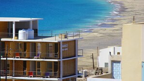 Un hôtel situé sur la côte, avec plusieurs étages, un balcon et une vue sur la plage et la mer.