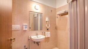 Ein Badezimmer mit Waschbecken, Spiegel, Handtuchhalter und Dusche.