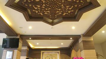 Un'area reception con un design a soffitto a forma di stella, una scrivania reception e un cartello di benvenuto incorniciato.