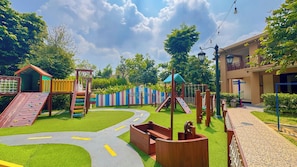 A playground with slides, climbing structures, and a winding path. - Lorin Syariah Hotel Solo (Surakarta)