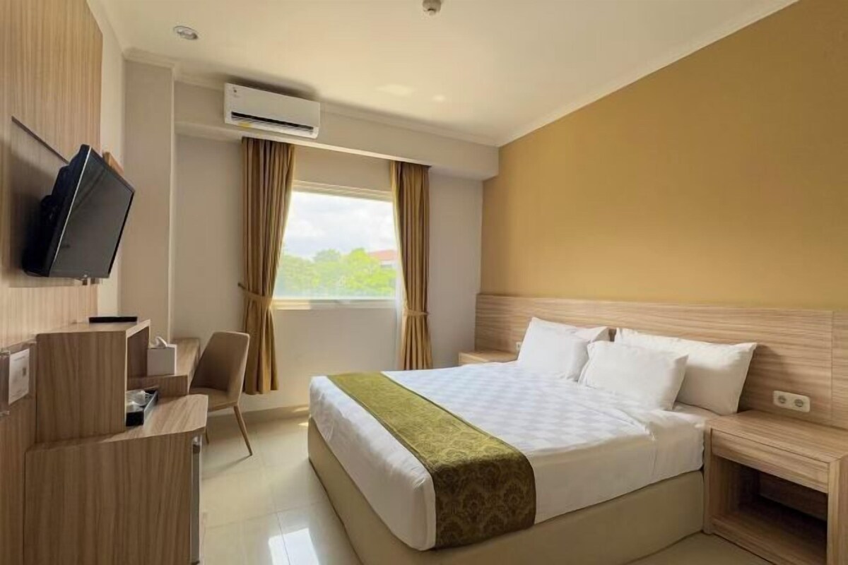 Una habitación de hotel con una cama, un escritorio, una silla y un televisor.