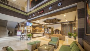 A spacious lobby with a reception desk, comfortable seating, and a staircase leading to an upper level. - Lorin Syariah Solo Hotel (Colomadu)