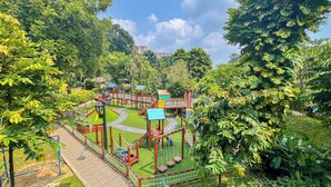 A playground with various play structures surrounded by lush greenery. - Lorin Syariah Solo Hotel (Colomadu)