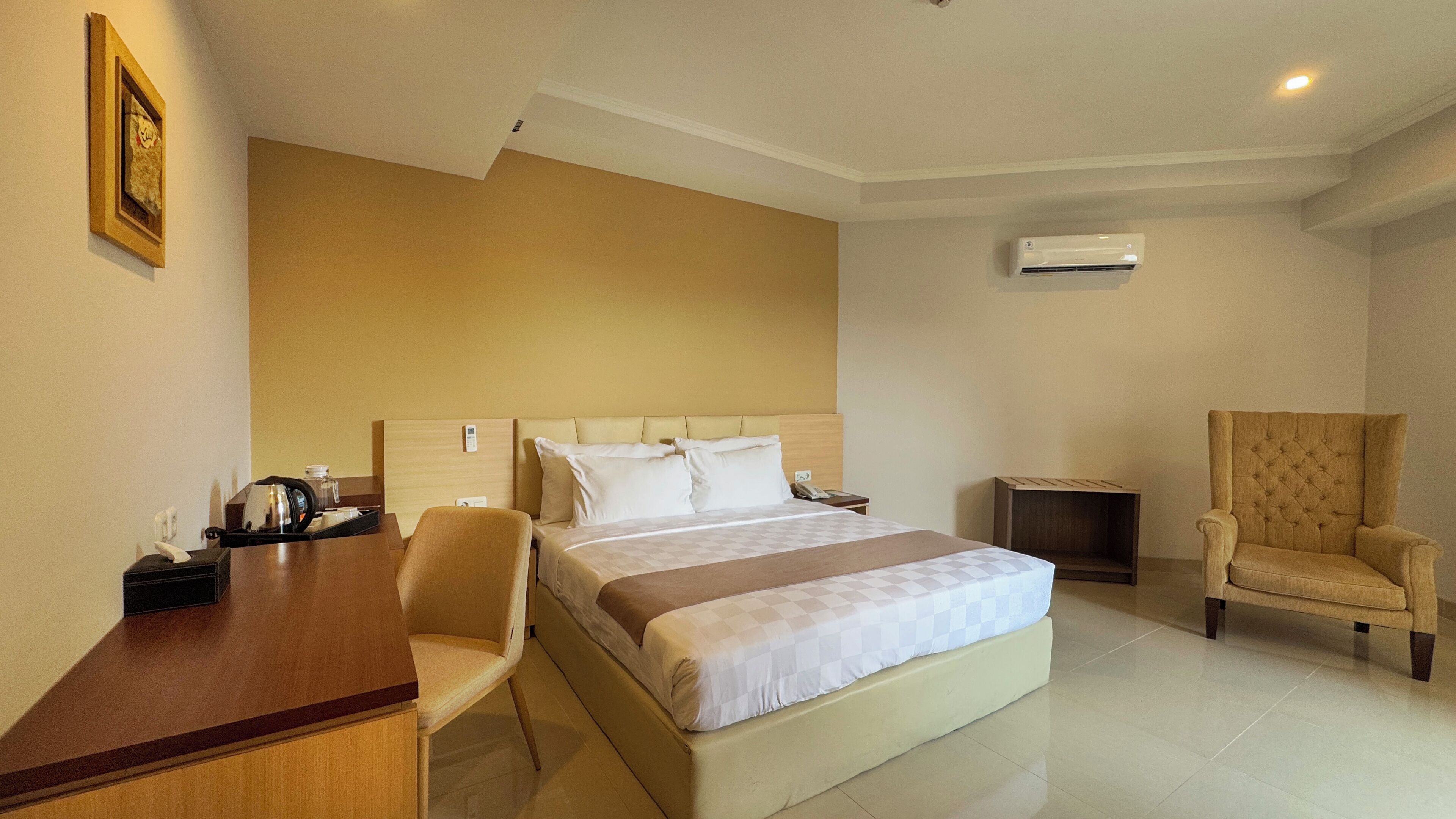 Una habitación de hotel con una cama, un escritorio, una silla y un equipo de aire acondicionado.