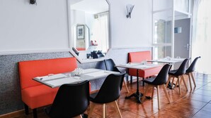 A modern dining area with red booths and black chairs, white tables, and a tiled floor. - Hôtel Notre Dame (Bordeaux)