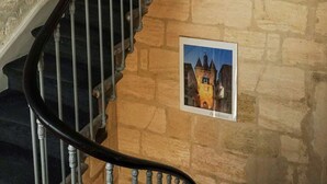 A spiral staircase with stone walls and a framed picture of a castle. - Hôtel Notre Dame (Bordeaux)