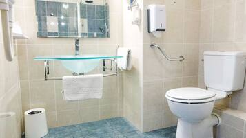 Un baño moderno con un lavamanos de vidrio, un inodoro blanco y un cabezal de ducha manual.