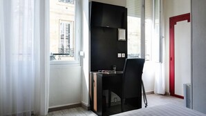A modern hotel room with a large window, a black desk, a chair, and a bed. - Hôtel Notre Dame (Bordeaux)