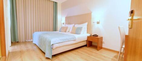A hotel room with a bed, bedside table, and a chair.