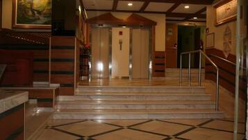 A hotel lobby with marble flooring, a staircase, and a reception desk.