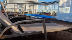 A poolside area with lounge chairs and a pool. - Baía Beach Hotel (Vila Real Santo Antonio)