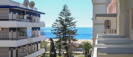 A multi-story building with balconies overlooking a beach.