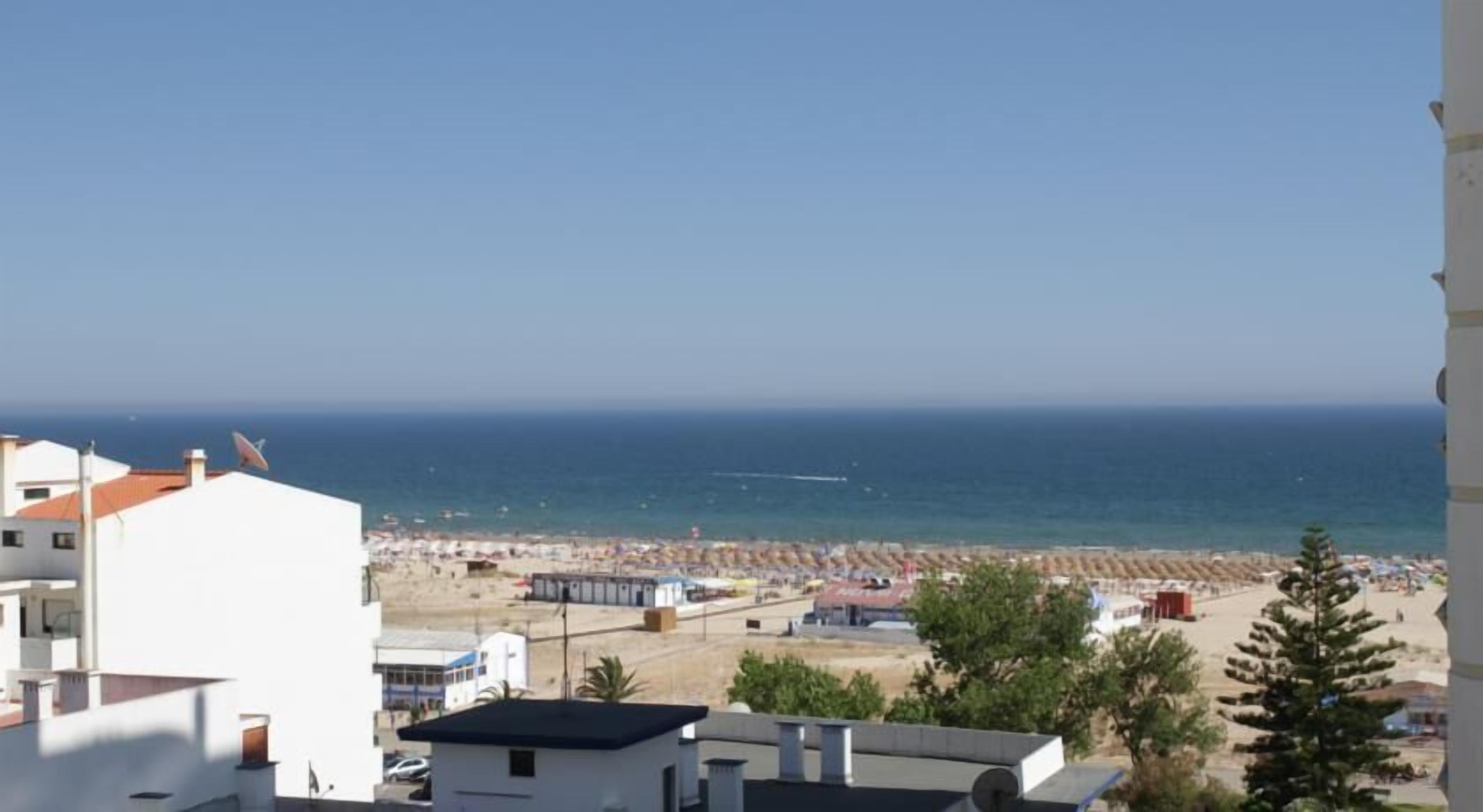 A coastal view with a beach, buildings, and a clear sky.