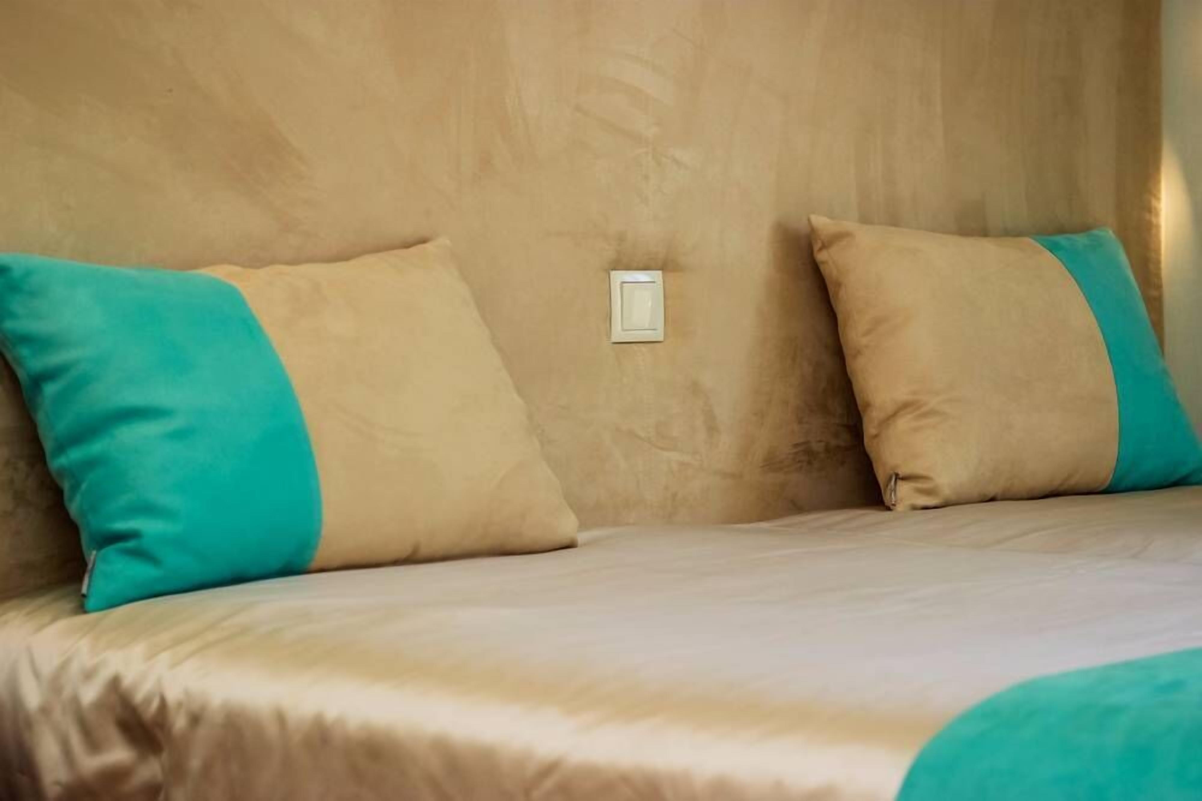 A bed with beige bedding and teal pillows.