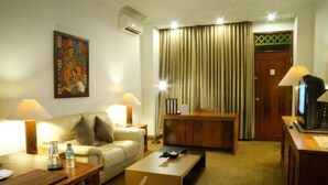 Una habitación de hotel con sofá, mesa de centro, escritorio y televisor.
