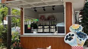 A small outdoor coffee shop with a wooden counter, a menu, and a sign advertising 6000s. - Jasmine Lodge (Siem Reap)