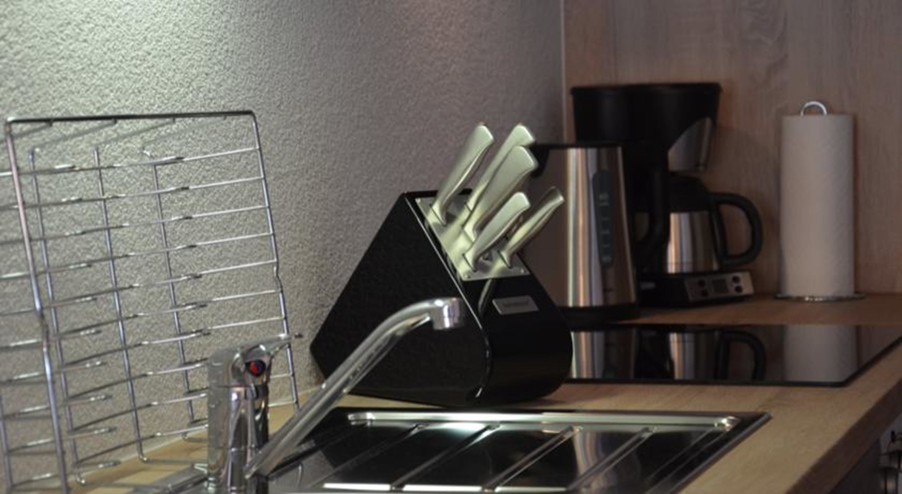 A kitchen with a sink, a coffee maker, and a utensil holder.