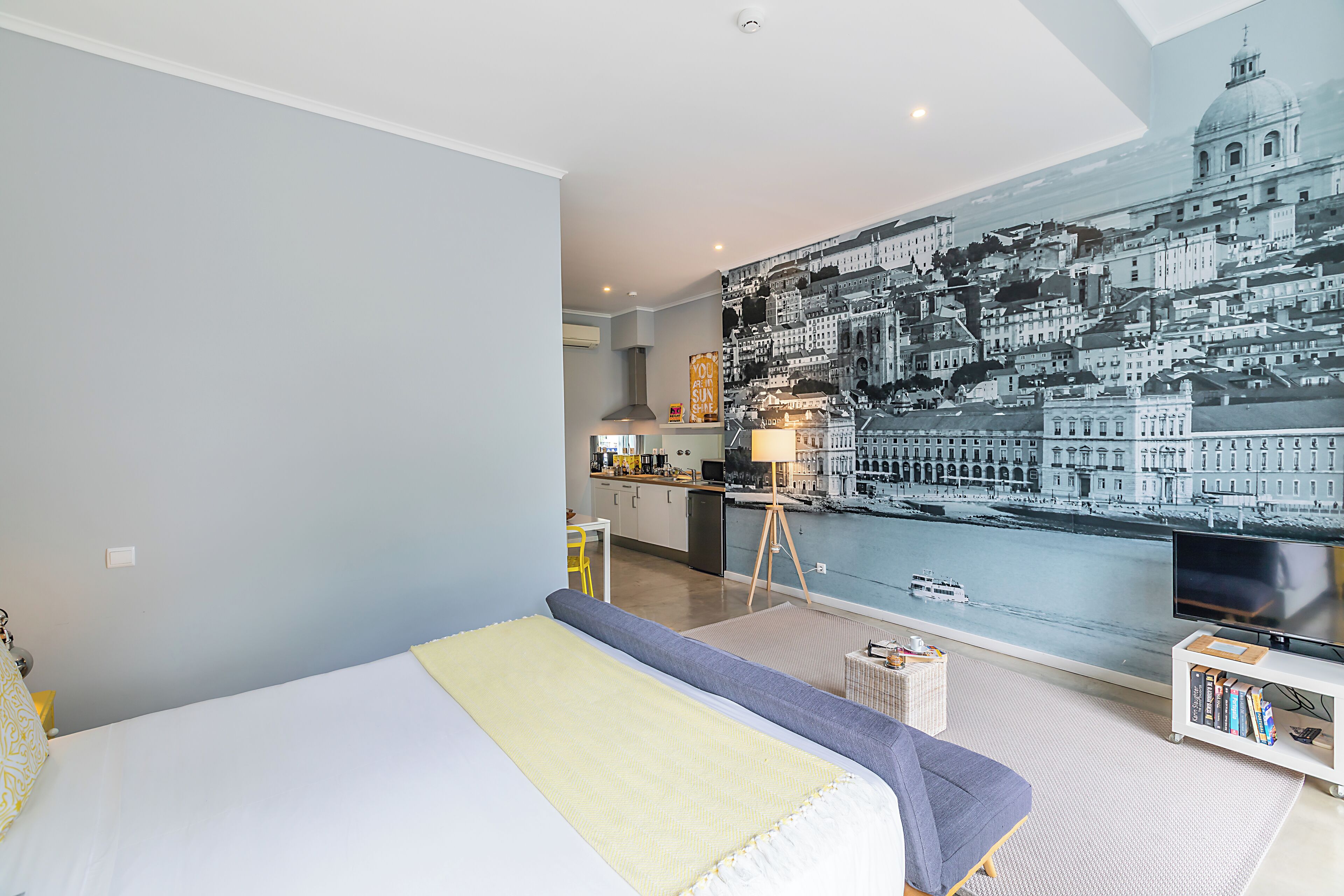 Ein modernes Hotelzimmer mit einem großen Bett, einem Fernseher und einem Wandgemälde mit Stadtansicht.