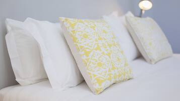 A bed with white and yellow patterned pillows and a bedside lamp.