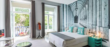 Un dormitorio moderno con una cama grande, vista a espacios verdes y un mural en la pared.
