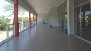 A covered corridor with glass walls, red pillars, and a tiled floor. - L Bajo Hotel (Labuan Bajo)