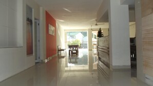 A modern hallway with a glossy floor, a red accent wall, and a view to a dining area. - L Bajo Hotel (Labuan Bajo)
