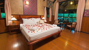 A spacious bedroom with a large bed, wooden flooring, and a view of the outdoors. - Sepilok Nature Resort (Sandakan)