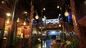 A spacious indoor area with wooden beams, hanging lights, and wicker furniture. - Sepilok Nature Resort (Sandakan)