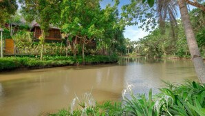 A riverside view with a wooden house and lush greenery. - Sepilok Nature Resort (Sandakan)