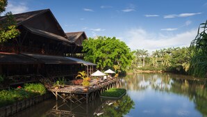 A riverside wooden structure with a dock, outdoor seating, and umbrellas. - Sepilok Nature Resort (Sandakan)
