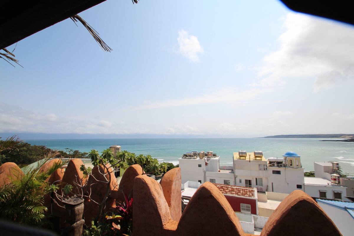 Blick auf die Küste mit Gebäuden, Palmen und blauem Himmel.