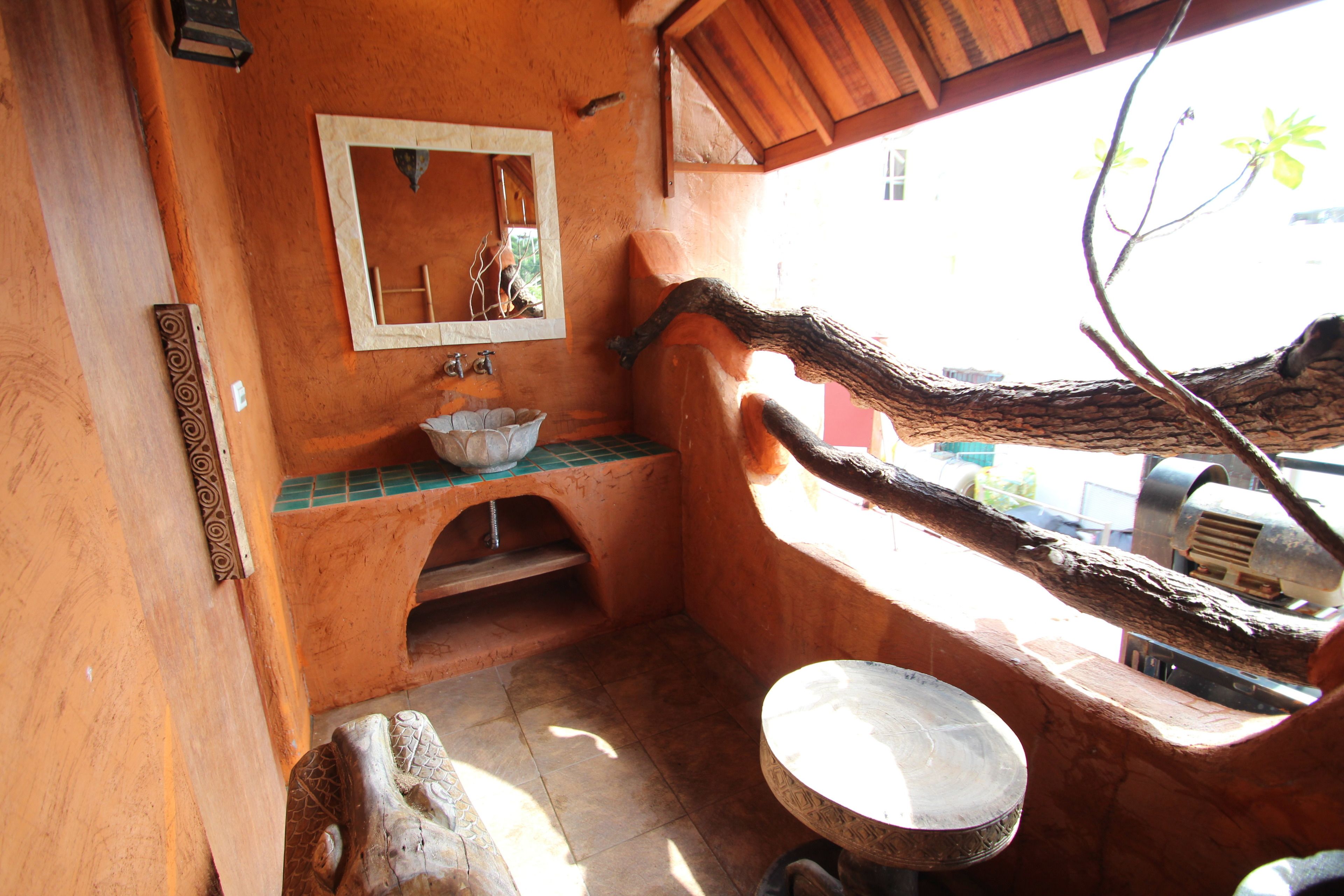 Un baño rústico con un lavabo de madera, un espejo y una pila de piedra.