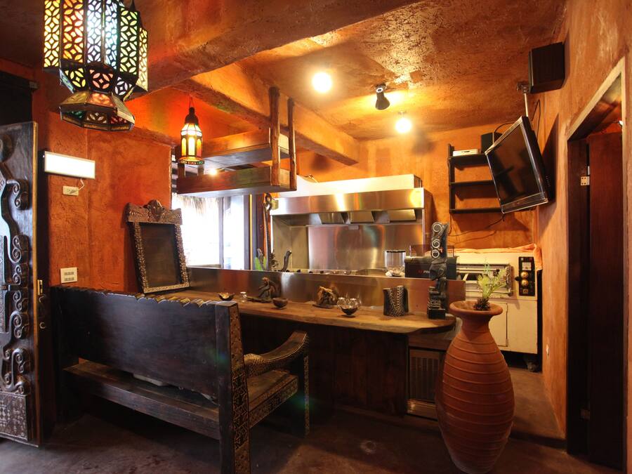 A rustic kitchen with a wooden bench, a large vase, and a hanging light fixture.