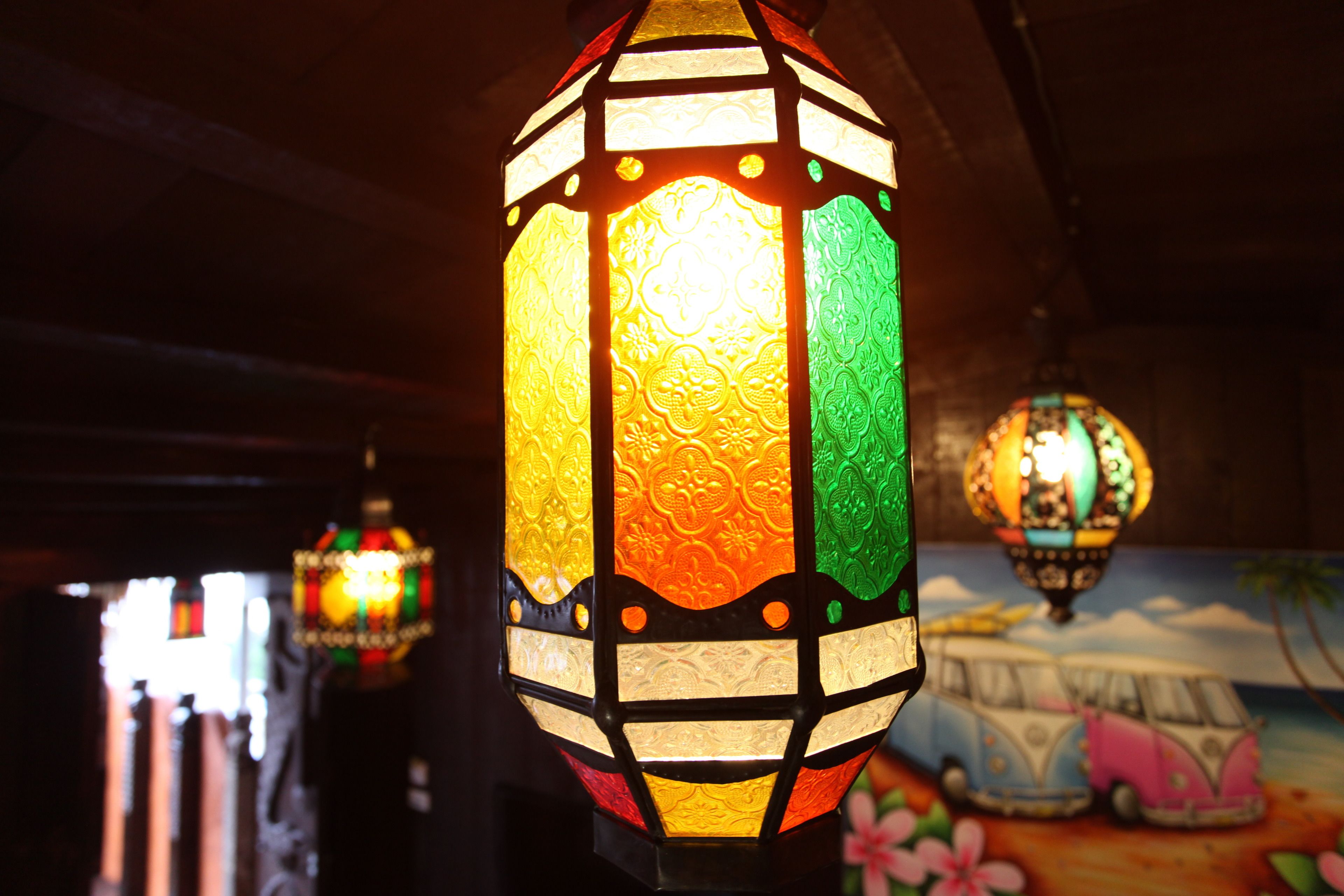 Un primer plano de un farol colorido y ricamente decorado colgando en una habitación con poca luz.