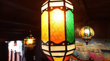 Un primer plano de un farol colorido y ricamente decorado colgando en una habitación con poca luz.