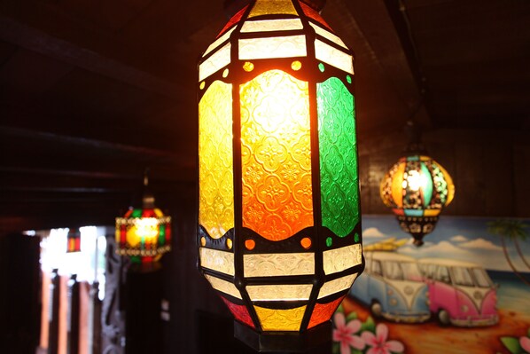 Un primer plano de un farol colorido y ricamente decorado colgando en una habitación con poca luz.