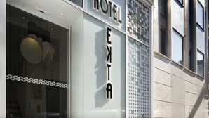 Hotellin sisäänkäynti, jossa on moderni julkisivu, suuret ikkunat ja näkyvissä oleva hissi.
