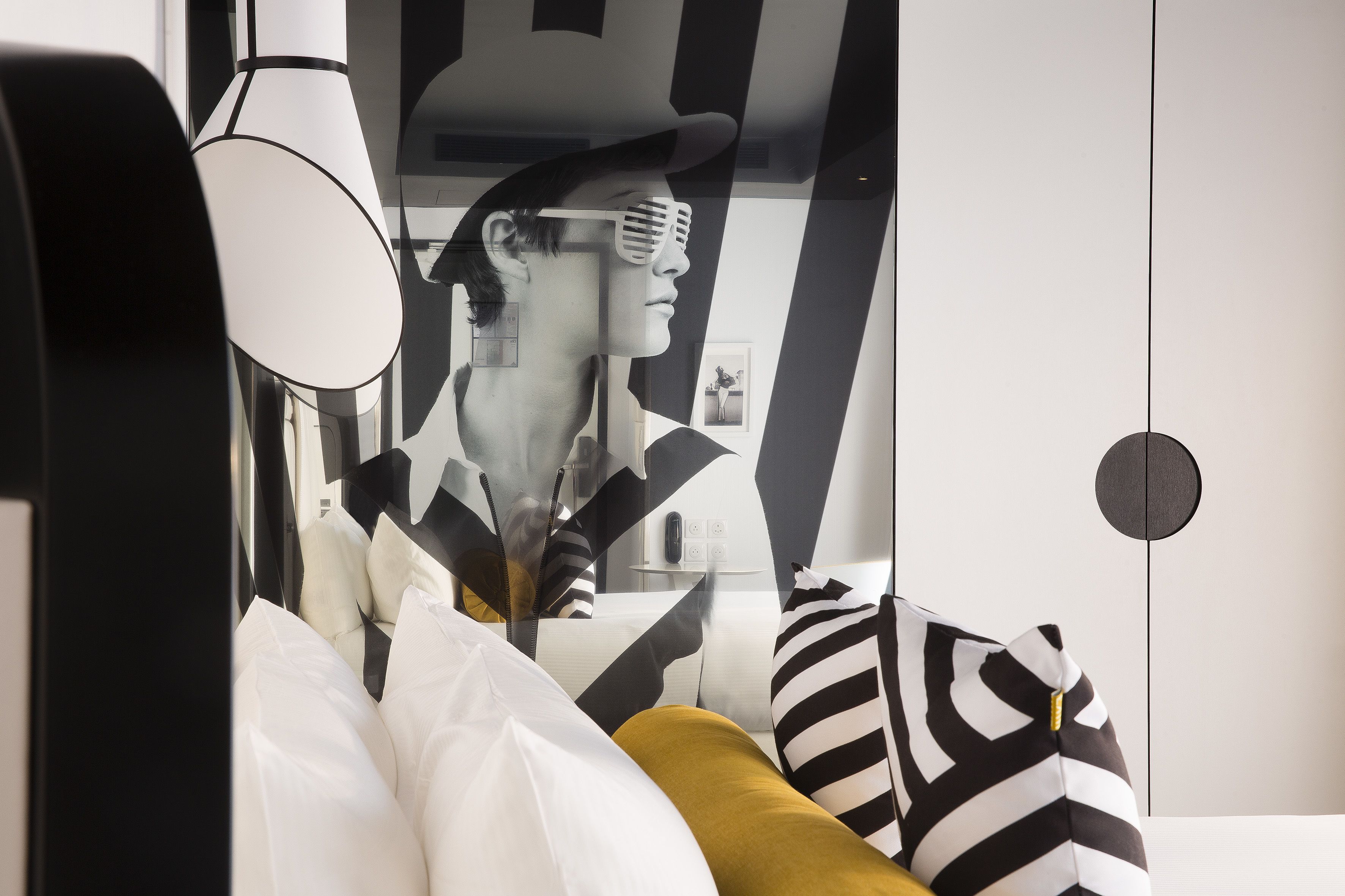 A modern room with a large mirror, a sofa with patterned cushions, and a minimalist decor style.
