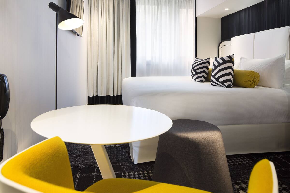 A hotel room with a bed, a round table, and a chair.