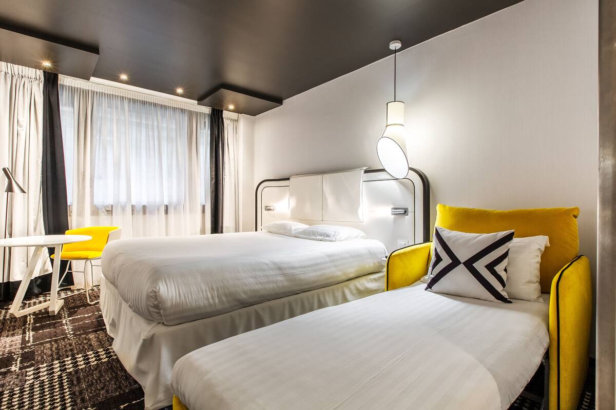 A hotel room with two beds, a desk, and a chair.