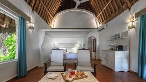 Una habitación con cama, dos sillones, una mesa de comedor con desayuno y una zona de cocina.